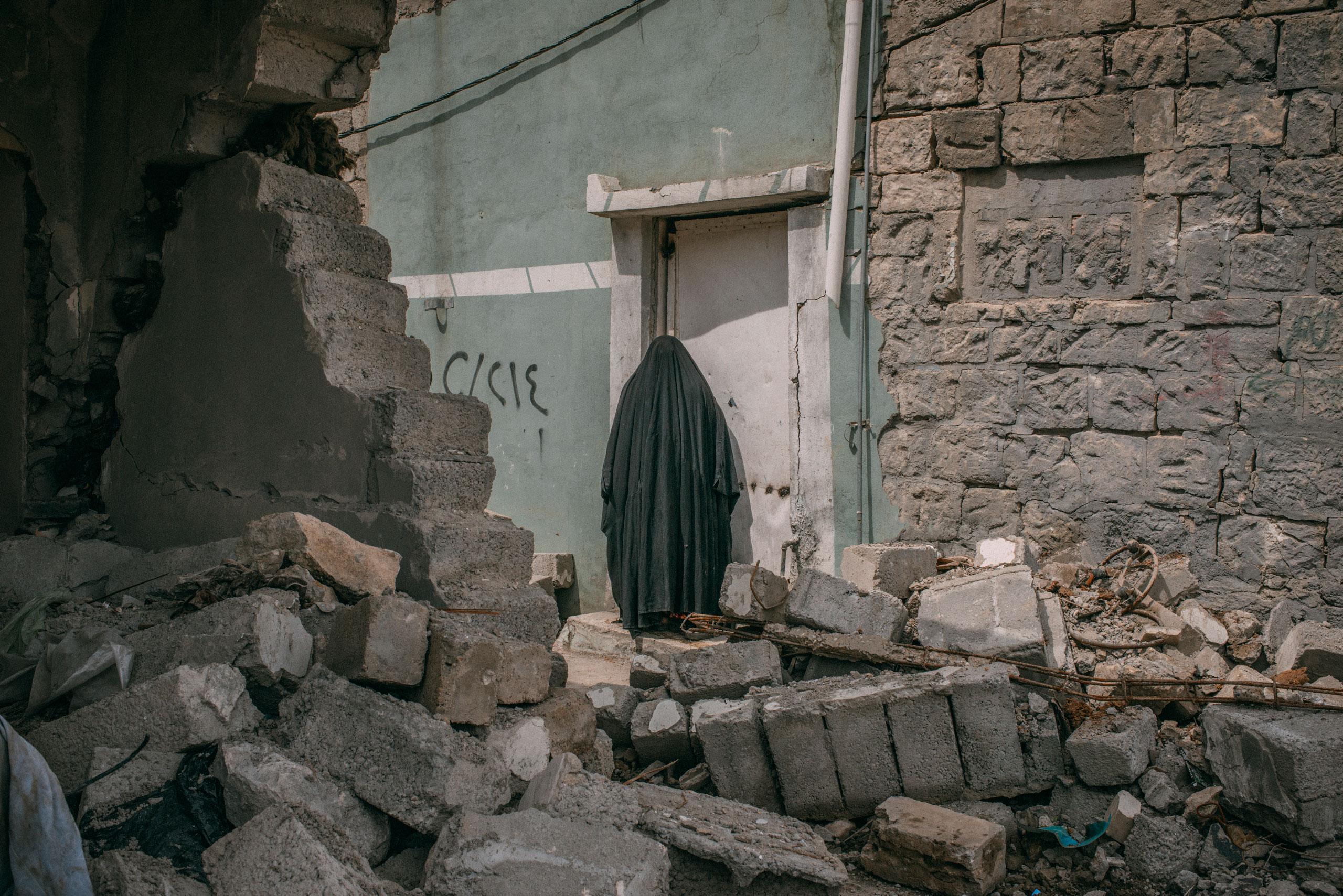 A woman stands among buildings damaged by a coalition airstrikes in Mansour district, in southwest Mosul. According to local people at leat 21 civilians have been used in the area as human shield by Isis.
