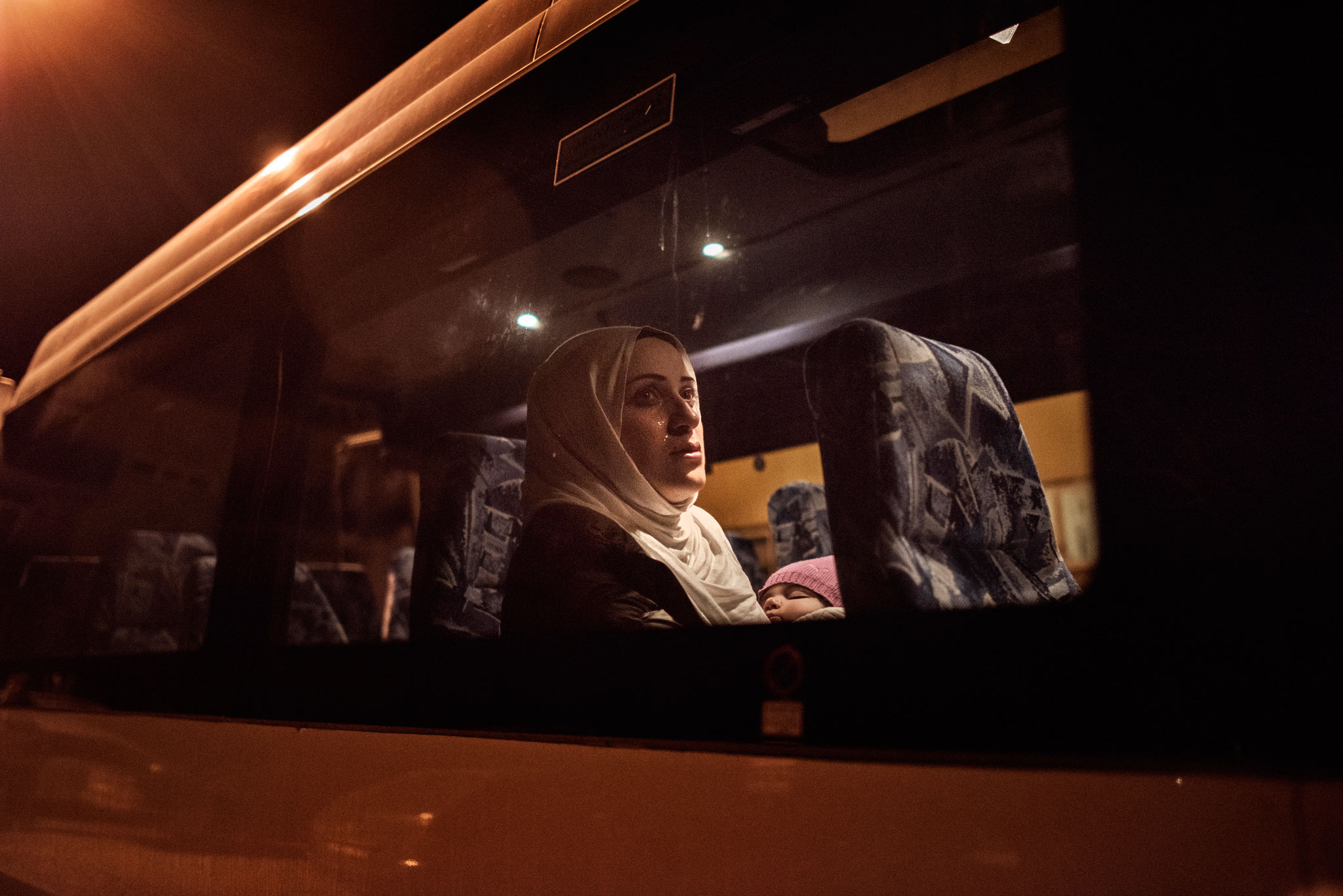 Syrian refugee Taimaa Abazlii weeps as she sits on the bus in front of her new apartment after a long, grueling day of travel and unheaval once again from Athens to their new home in Polva, Estonia, April 20, 2017.  The family, along with Muhannad's brother's family of Mufeed and Iyman Ateek and their two children, were relocated to a small village of 6000 people in the middle of the forest, called Polva; they feared it would be impossible to integrate and make a life in such a remote place.  After over one year of traveling from war-town Syria, making their way from Turkey to Greece, waiting in greece for asylum, the family is finally relocating to Estonia.
