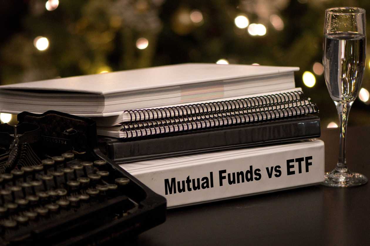 Mutual Funds vs etf written on a binder next to a typewriter and a champagne glass 