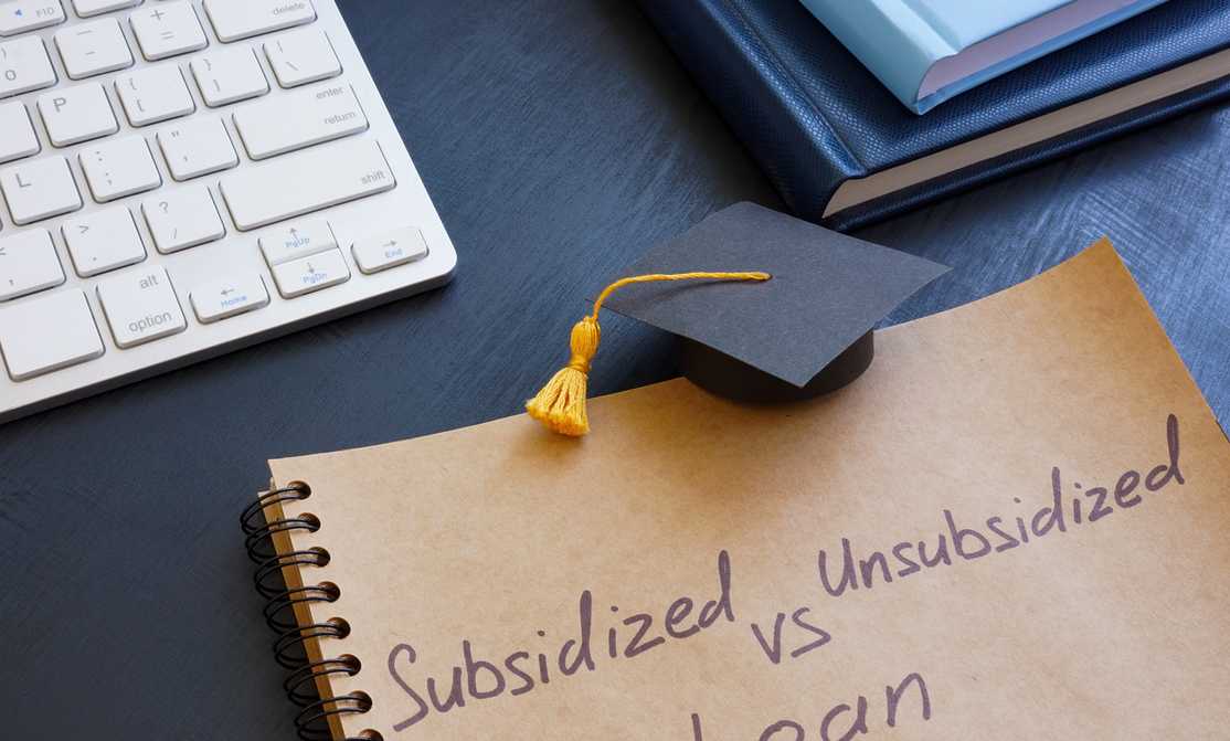 Subsidized vs. Unsubsidized Loan written on a notepad with a student graduation hat on it