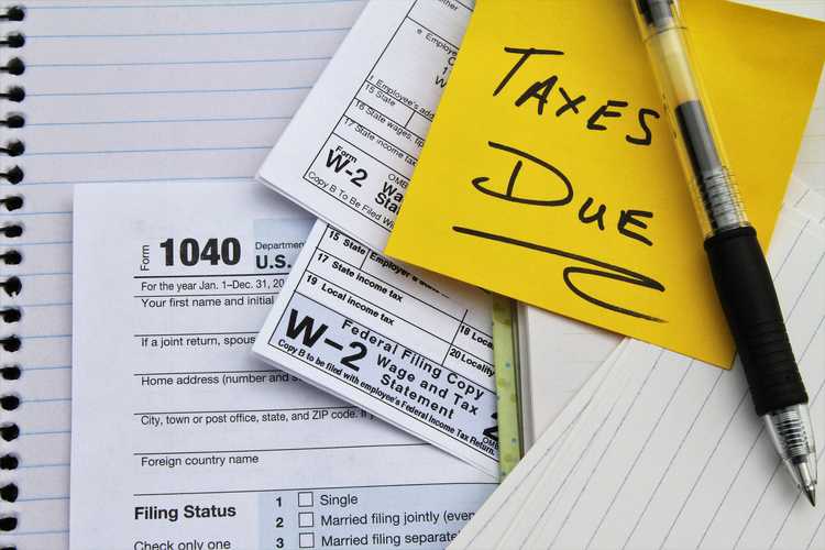 Tax return forms and wage statements with note Taxes Due