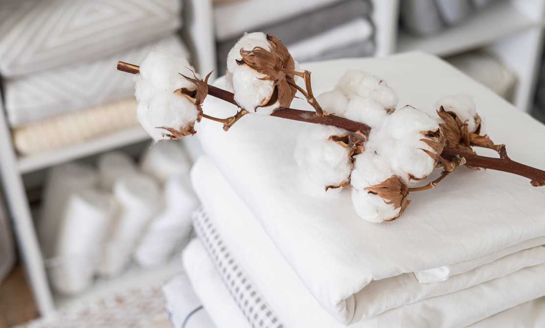 Cotton branch with pile of folded bed sheets and blankets