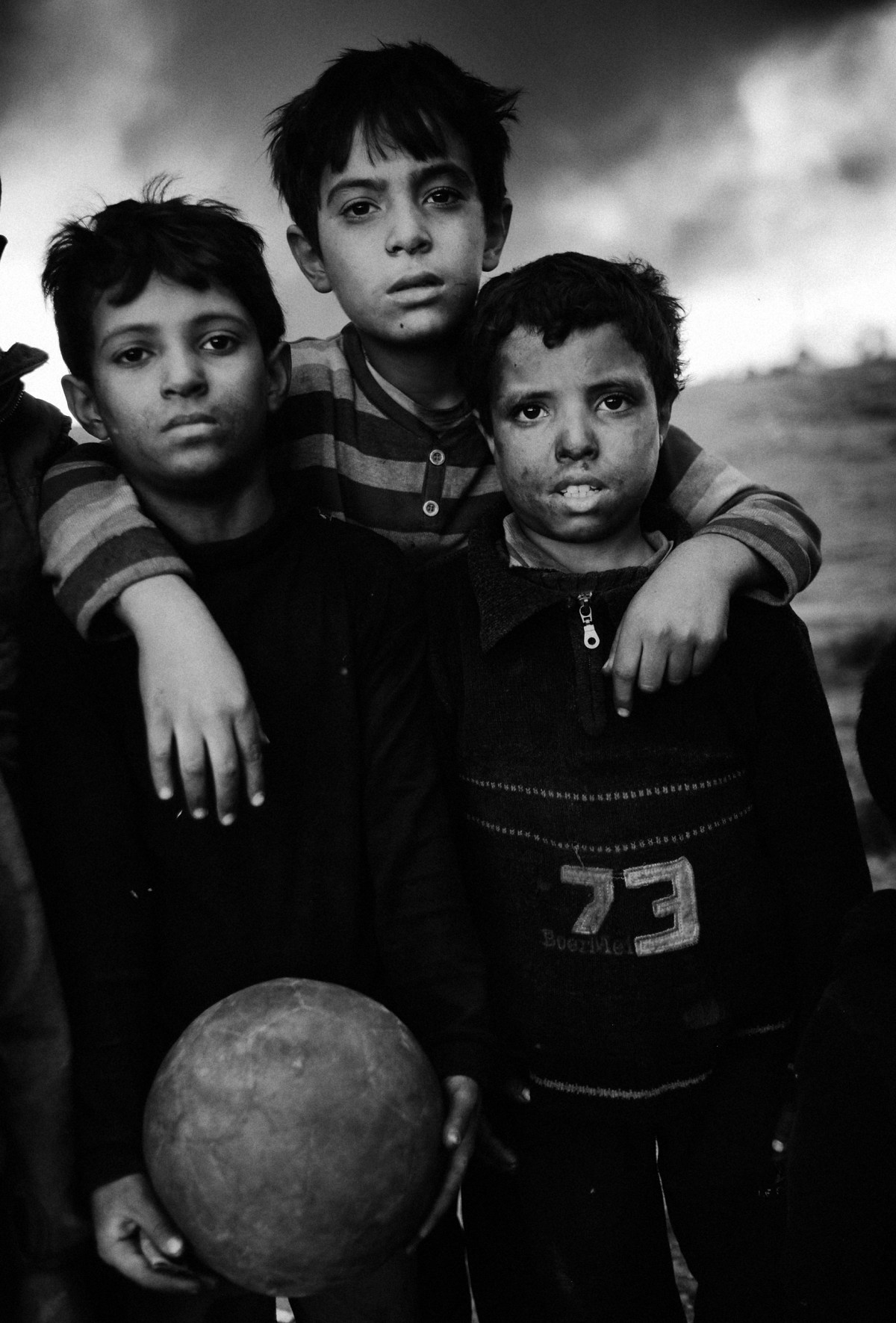 three boys at the football pitch in the city Qayyara, south of Mosul. The dense plumes of smoke are emanating from multiple sites about 30 miles (50 km) south of Mosul. The fires were deliberately set by ISIS militants before abandoning the city. The smoke has been persistent over the past three months, blotting out the sun hours before nightfall and creating major health issue for mainly the children in the area.