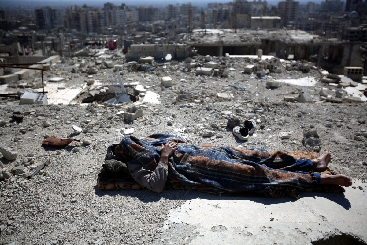 A man sleeps on the roof of a damaged building in the Barzeh neighborhood of Damascus on Feb. 17. Mohammed BadraÃ¢Â€Â”EPA