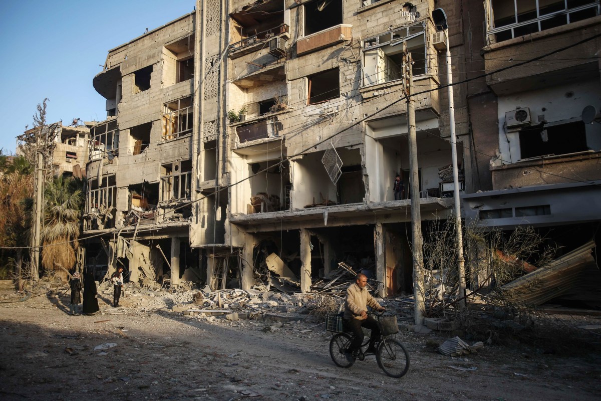 A man cycles past destroyed buildings in Douma on Nov. 22. Mohammed BadraÃ¢Â€Â”EPA