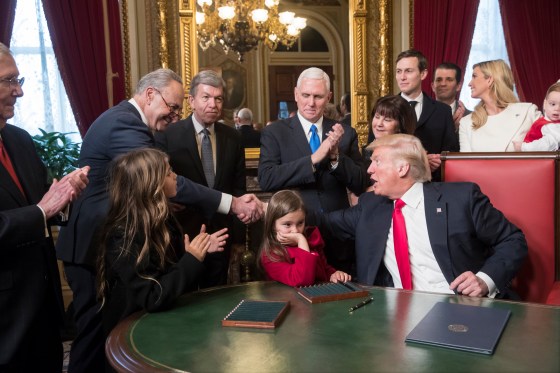 President Donald Trump shakes hands with Senate Minority Leader Charles Schumer of N.Y, as he is joined by the Congressional leadership and his family while he formally signs his cabinet nominations into law, Jan. 20, 2017.