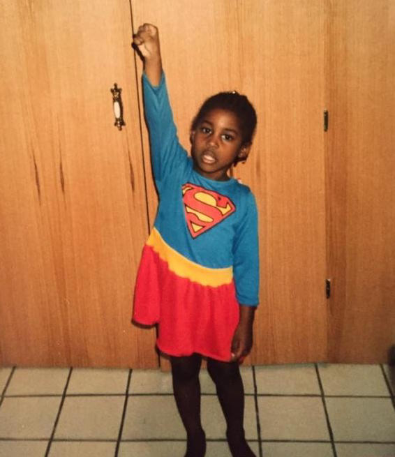 Issa Rae as a young girl posing in a Supergirl costume.