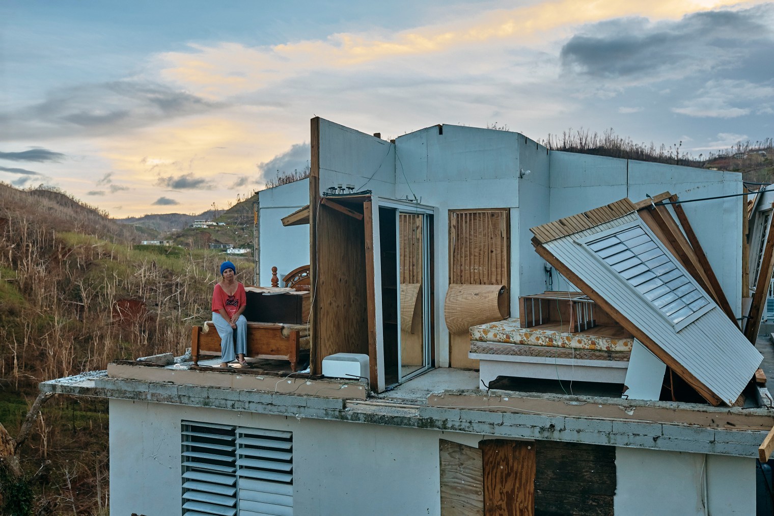 Wilmair Flores, 55, poses on a bed at her house damaged by Hurricane Maria in Barranquitas, Puerto Rico, Oct. 2, 2017